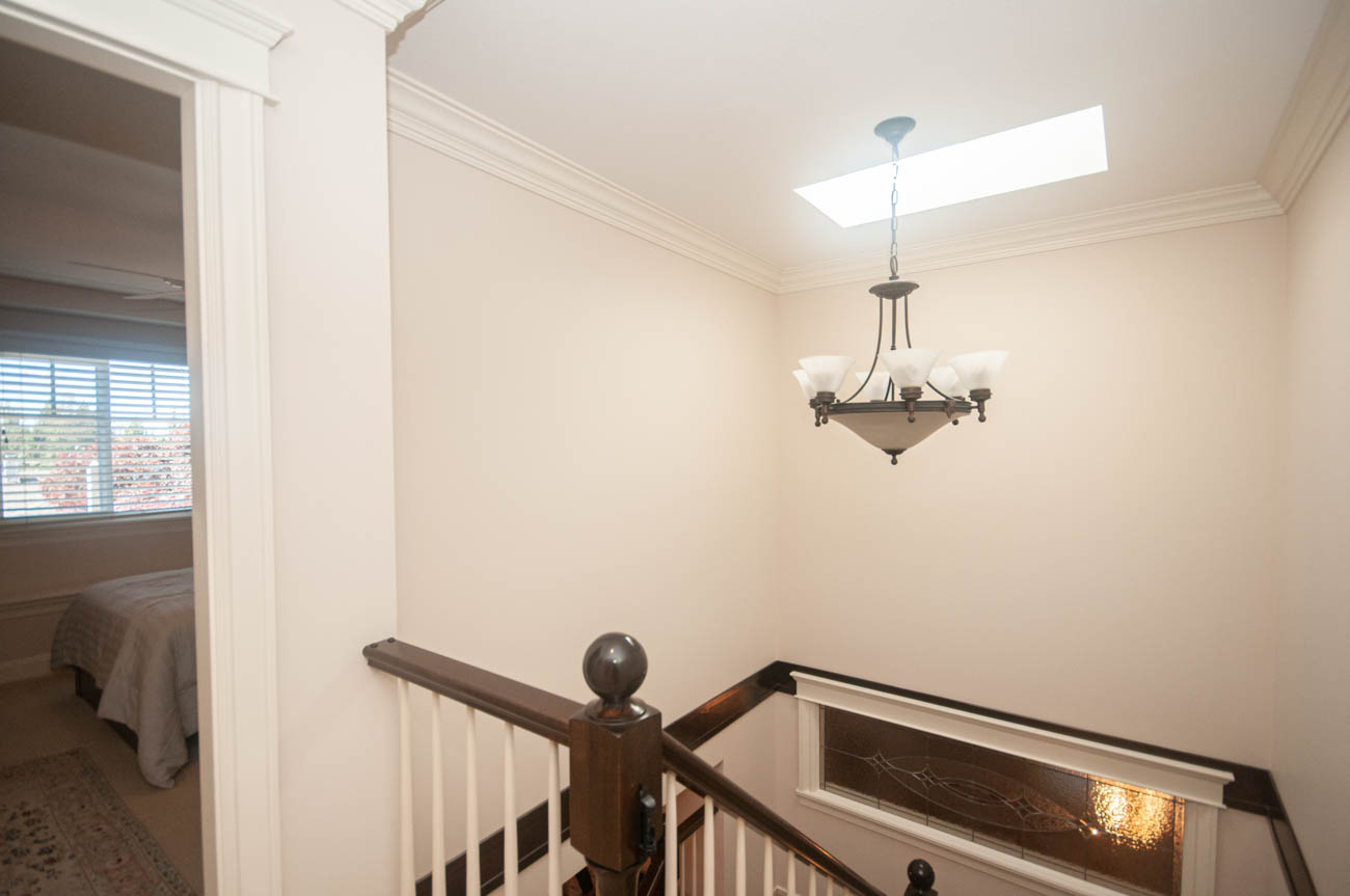 Foyer with chandelier and view of bedroom beyond, elegant staircase leading up. - 3440 Wellington Crescent, North Vancouver