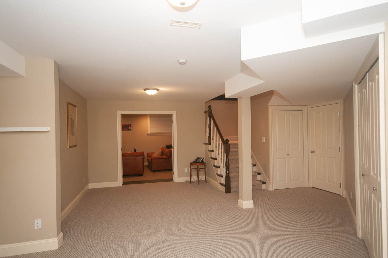 Open-concept living area with carpeted floors and a staircase leading to upper levels. - 3440 Wellington Crescent, North Vancouver