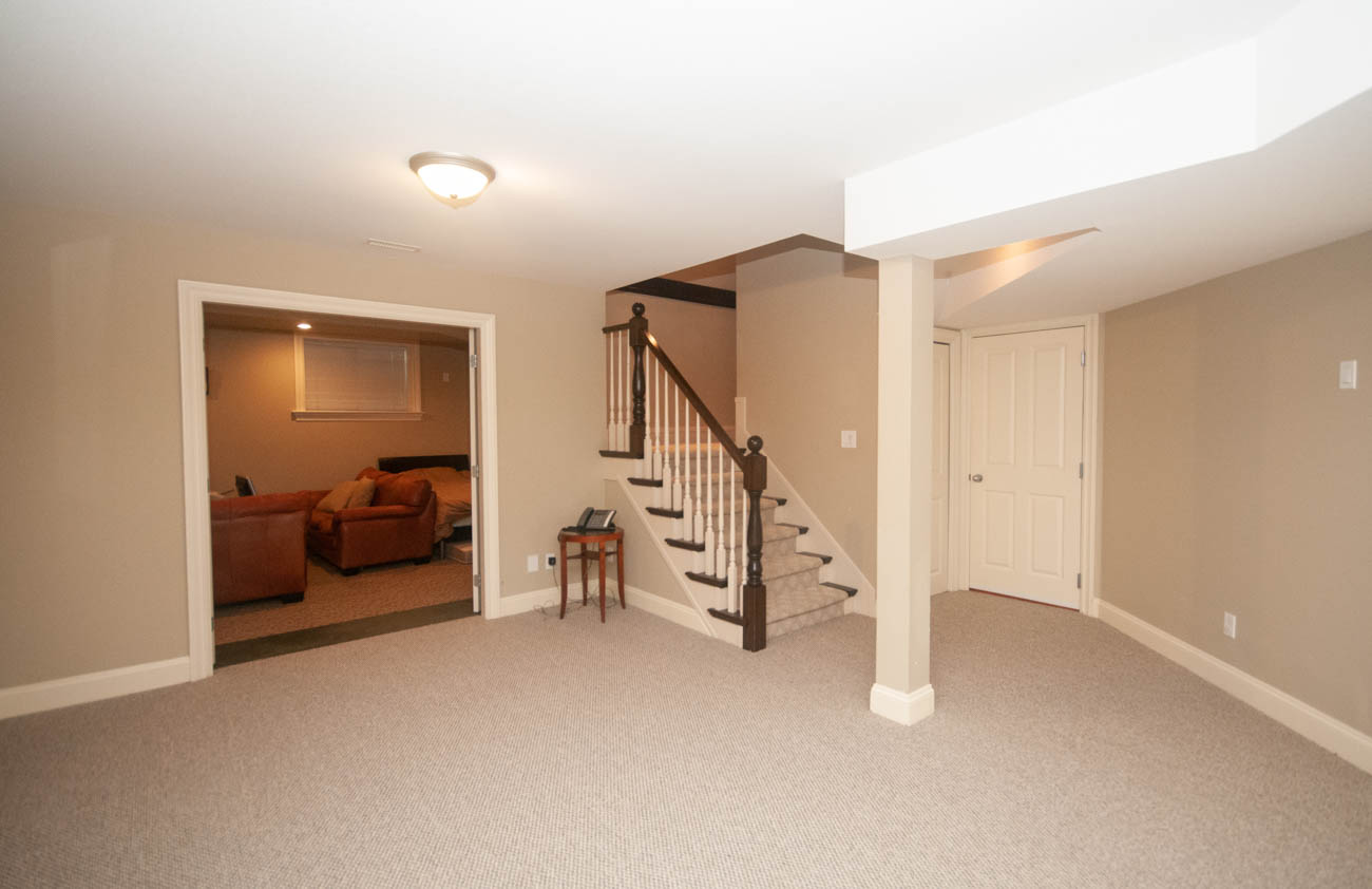 Spacious living area with carpeted floors and a staircase leading to upper levels. - 3440 Wellington Crescent, North Vancouver