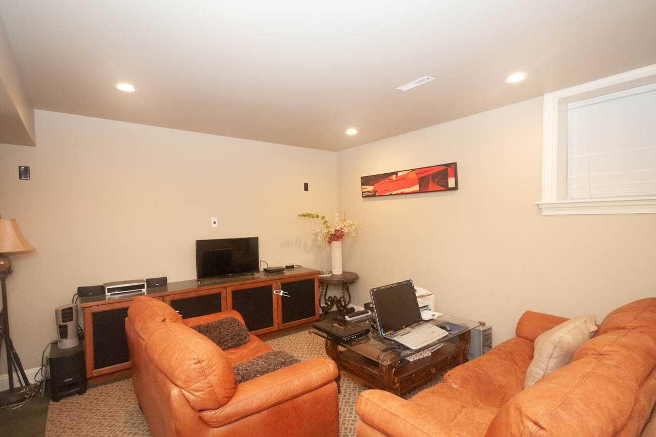 Furnished living room with orange leather furniture and a flat-screen TV. - 3440 Wellington Crescent, North Vancouver