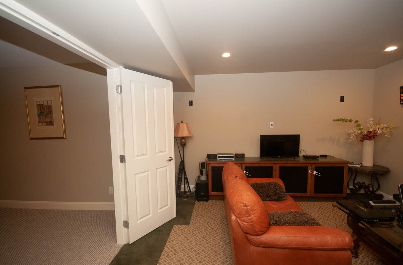 Bright living room with orange leather chairs and wooden entertainment center. - 3440 Wellington Crescent, North Vancouver