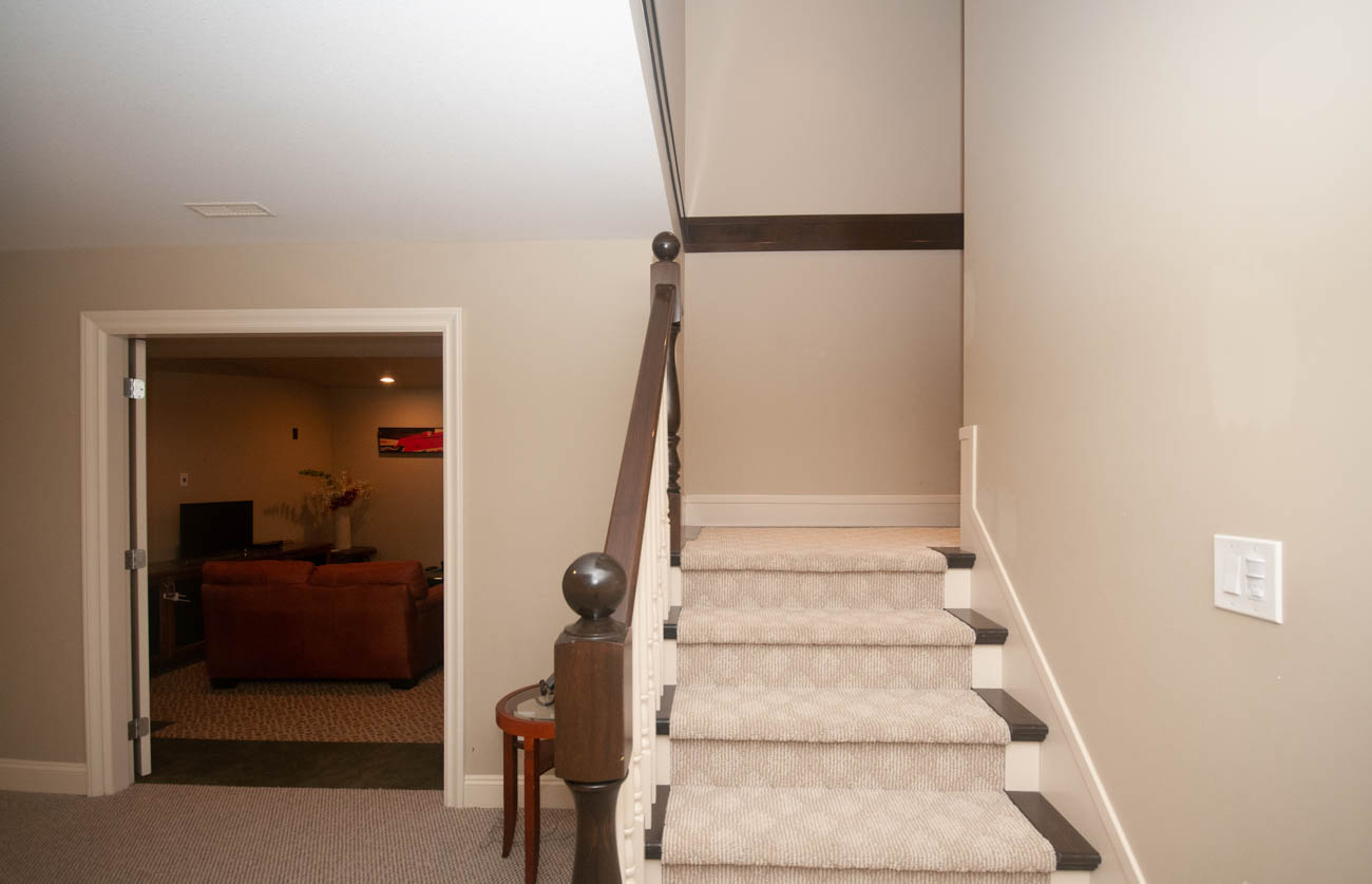 Furnished living room with a cozy sofa and a view of the staircase leading to the upper level. - 3440 Wellington Crescent, North Vancouver