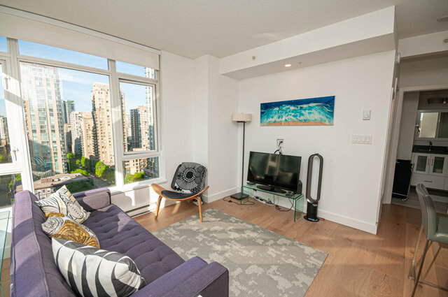 The living room contains a purple sofa with patterned cushions, a wooden chair with a black and white cushion, a flat-screen 