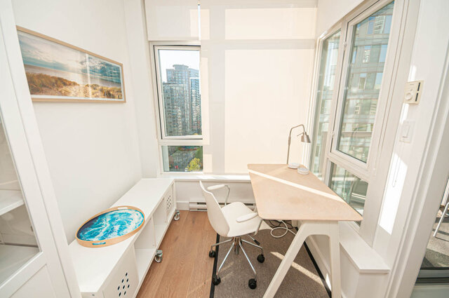 A den featuring a desk, office chair, built-in storage unit, large windows with city views, and hardwood floors