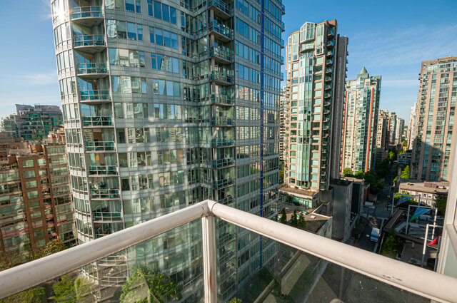 A balcony with a metal railing overlooking high-rise buildings and a clear blue sky. - 1306-480 Robson Street, Vancouver Downtown