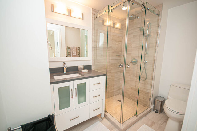 This bathroom contains a vanity sink, mirror, glass shower enclosure, and toilet. - 1306-480 Robson Street, Vancouver Downtown