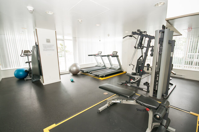 The gym contains treadmills, weight machines, exercise balls, and large windows. - 1306-480 Robson Street, Vancouver Downtown