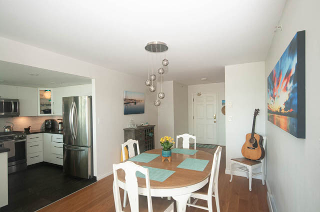 Open-concept dining and kitchen area with modern light fixture and hardwood floors. - 801-1128 Quebec st, Vancouver Downtown