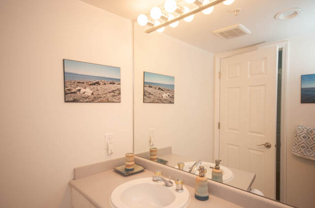 Spacious bathroom with white countertop, gold faucet, and beach-themed wall art. - 801-1128 Quebec st, Vancouver Downtown