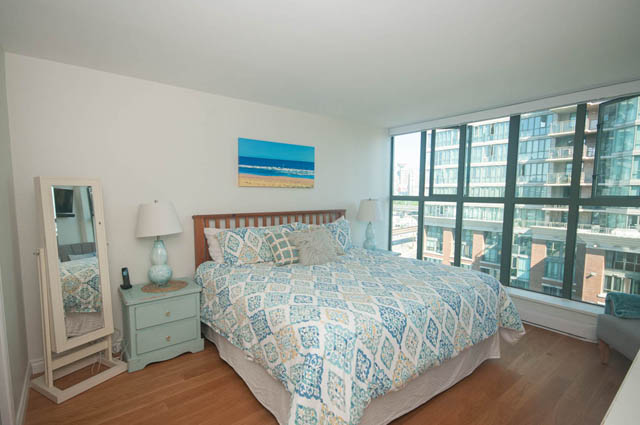 Spacious bedroom with hardwood floors, city view, and a cozy bed setup. - 801-1128 Quebec st, Vancouver Downtown