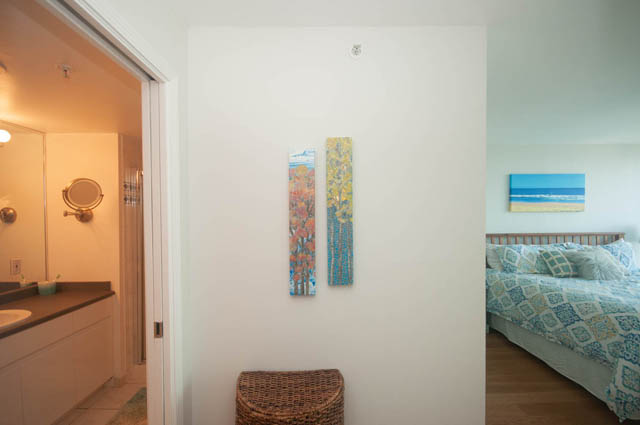Spacious bedroom with hardwood floors, beach-themed artwork, and a cozy bed setup. - 801-1128 Quebec st, Vancouver Downtown