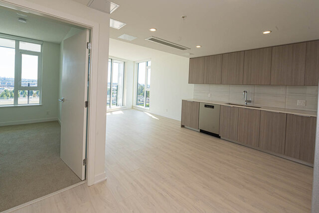 Bright kitchen with light wood cabinets and hardwood floors, featuring a city view through large windows. - 1105 - 1401 Hunter Street, North Vancouver