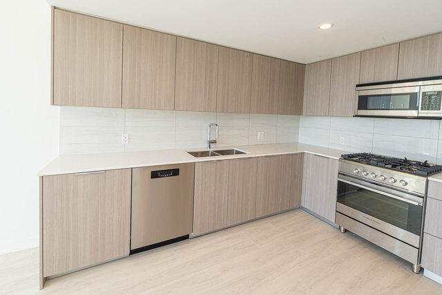 Bright kitchen with light wood cabinets, white countertops, and stainless steel appliances. - 1105 - 1401 Hunter Street, North Vancouver