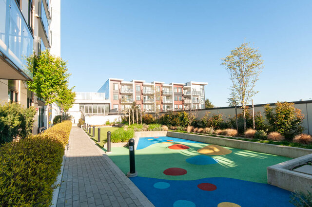 Spacious 1-bedroom + den with vibrant outdoor mini-golf course and modern apartment buildings in the background.