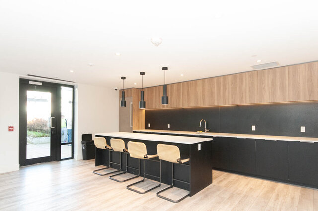 Modern kitchen with sleek black cabinetry, light wood countertops, and pendant lighting. - 1105 - 1401 Hunter Street, North Vancouver