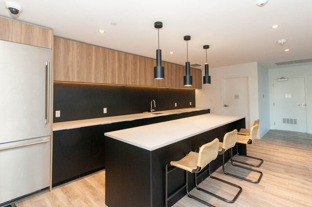 Modern kitchen with sleek white countertops, black backsplash, and pendant lights. - 1105 - 1401 Hunter Street, North Vancouver