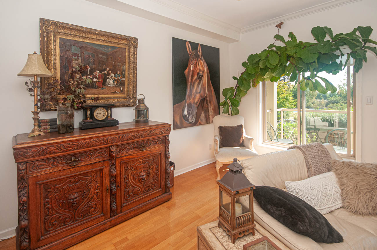 Spacious living room with ornate wooden furniture, a horse portrait, and a view of the balcony. - 1207 Marine Dr, West Vancouver