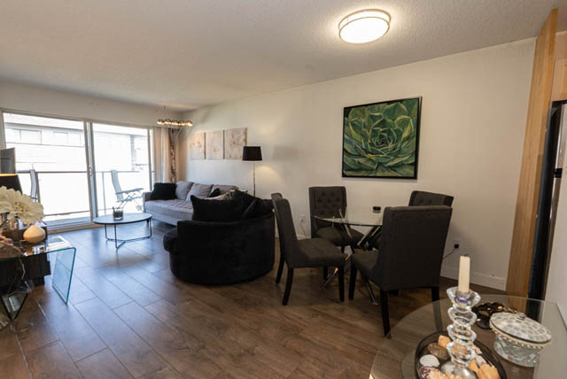 Spacious living room with hardwood floors, city view, and modern decor. - 306 - 212 Forbes Ave, North Vancouver
