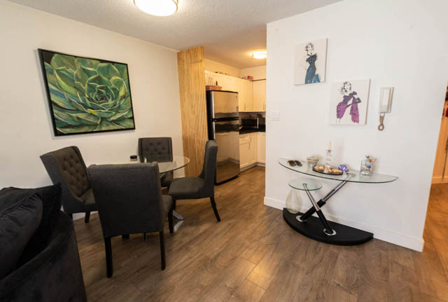 Bright dining area with modern artwork and black chairs, hardwood floors. - 306 - 212 Forbes Ave, North Vancouver