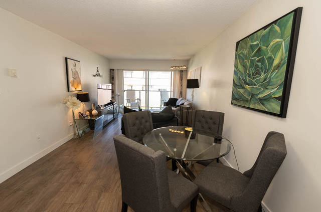 Furnished living room with hardwood floors, city view, and modern decor. - 306 - 212 Forbes Ave, North Vancouver