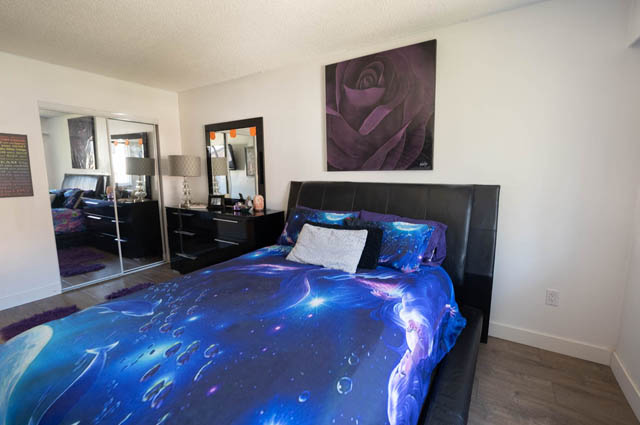 Bright bedroom with blue galaxy-themed bedding and large rose artwork above the bed. - 306 - 212 Forbes Ave, North Vancouver