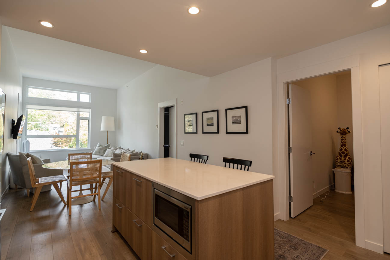 Bright kitchen with wooden countertops and hardwood floors, leading to a cozy living area with a city view. - 308 - 715 W15th Street, North Vancouver
