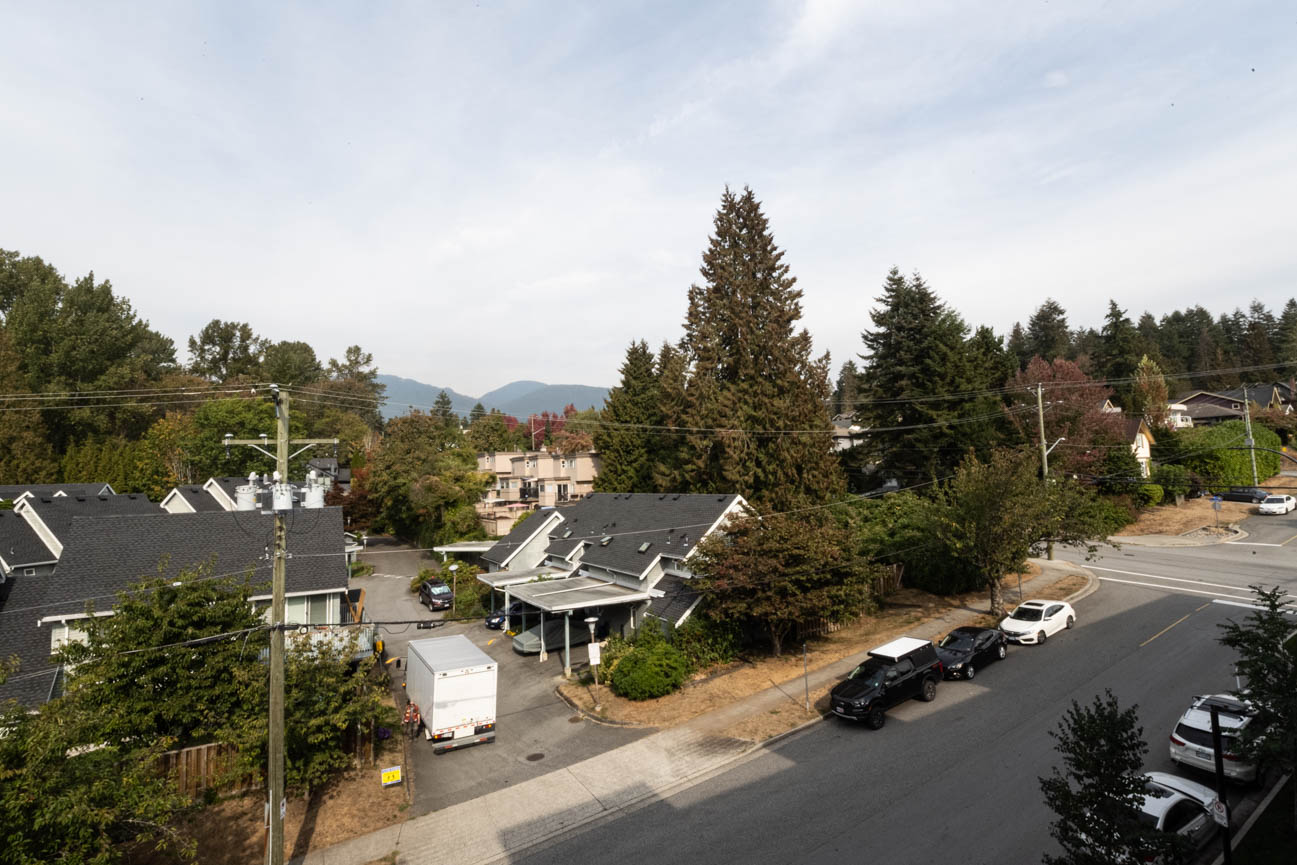Bright living room with large windows, city view, and modern furnishings. - 308 - 715 W15th Street, North Vancouver