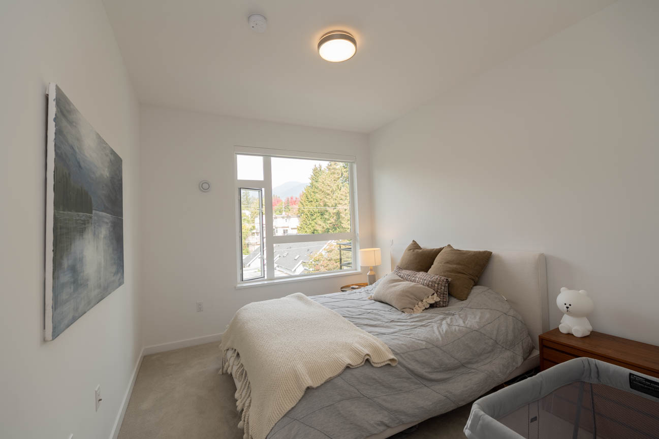 Furnished bedroom with a city view and modern decor. - 308 - 715 W15th Street, North Vancouver