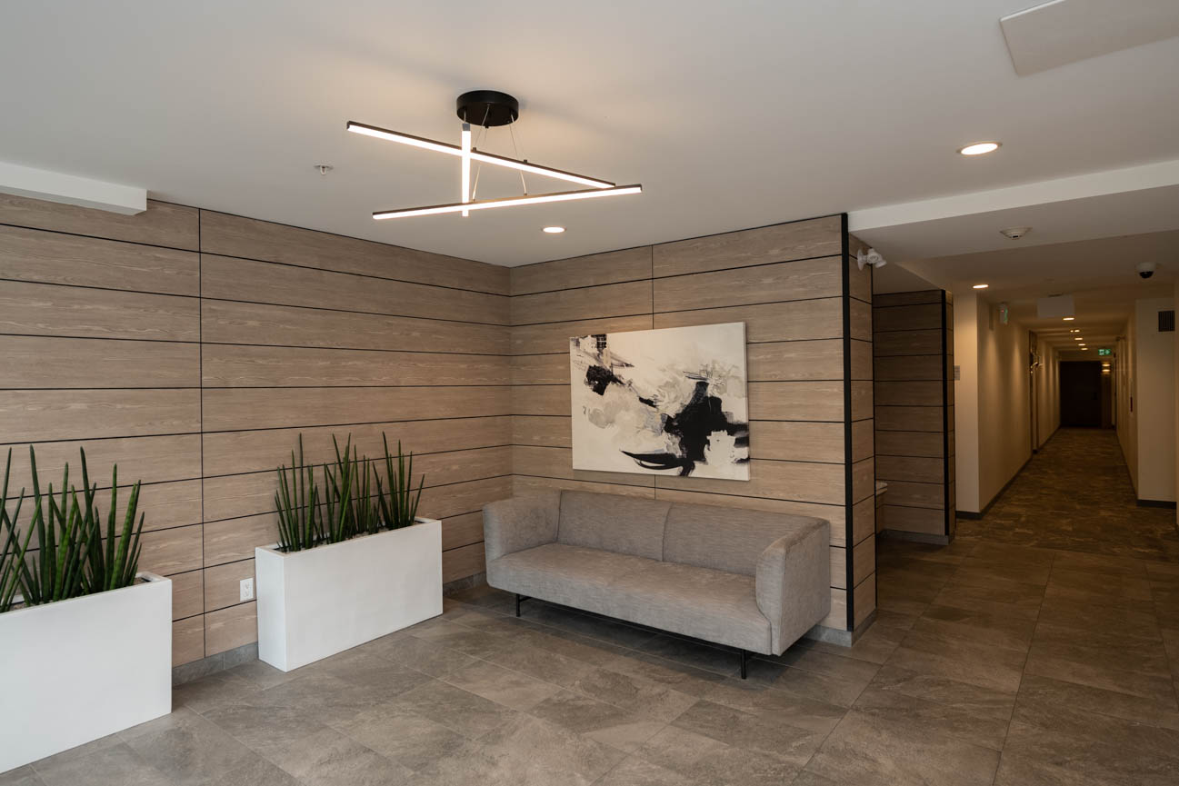 Furnished living room with modern wood paneling, abstract art, and plush seating. - 308 - 715 W15th Street, North Vancouver