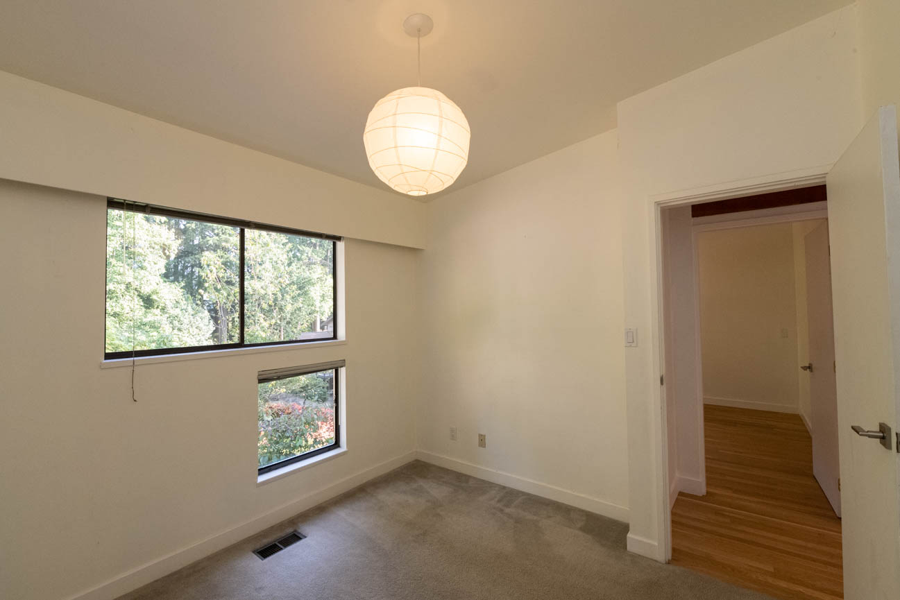 Spacious bedroom with hardwood floors and a view of trees. - Upper - 3248 Robinson Road, North Vancouver