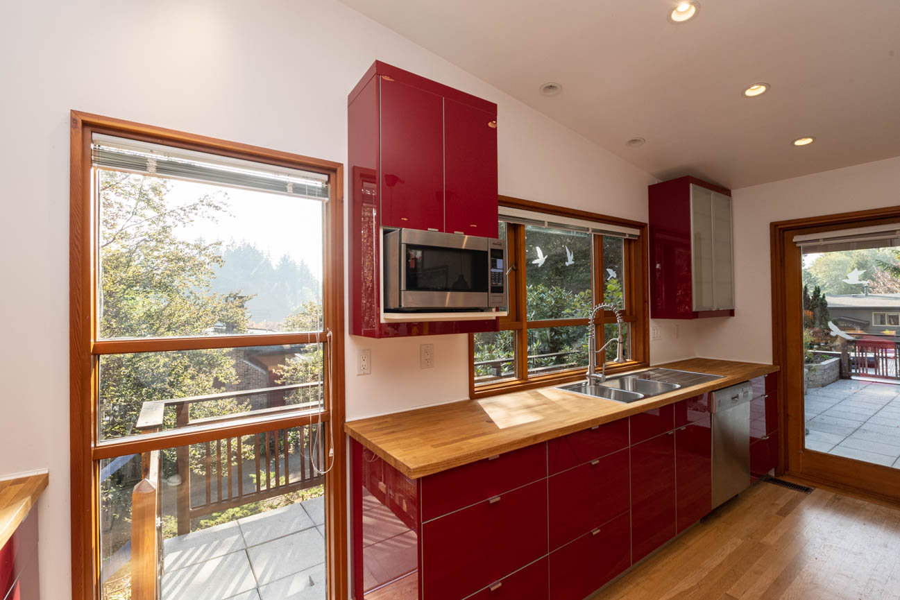 Bright kitchen with red cabinets, wooden countertops, and city view. - Upper - 3248 Robinson Road, North Vancouver