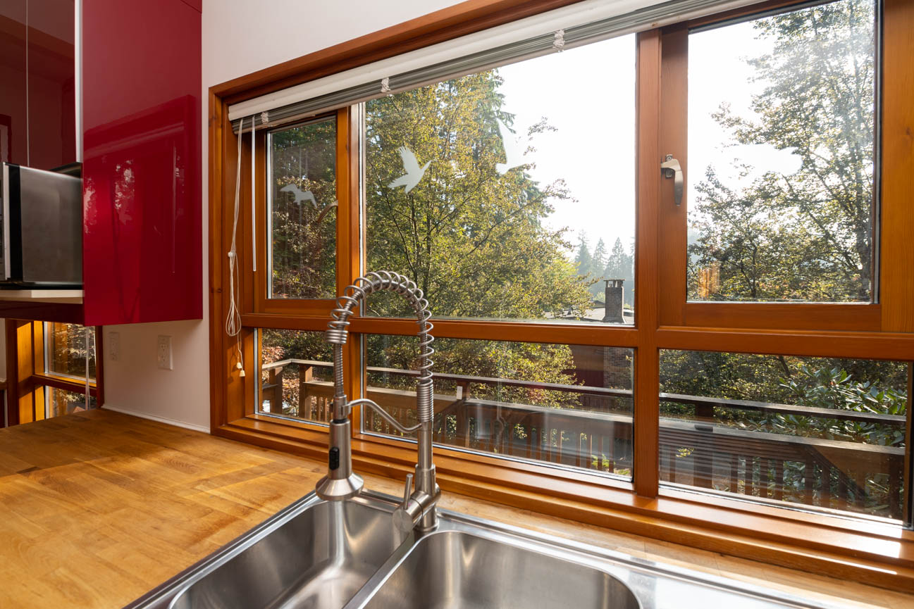 Bright kitchen with hardwood floors, large windows, and a view of trees. - Upper - 3248 Robinson Road, North Vancouver