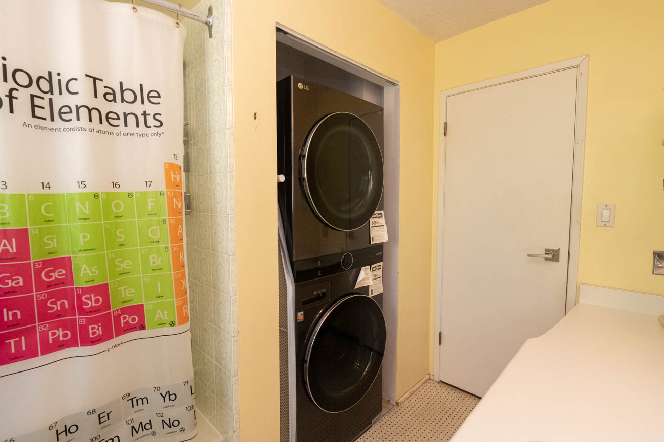 Laundry room with LG dryer, periodic table shower curtain, and pegboard floor. - Upper - 3248 Robinson Road, North Vancouver