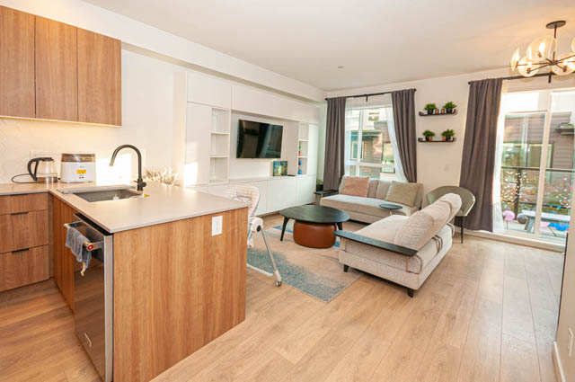 Bright kitchen with wooden countertops and hardwood floors, leading to a cozy living area with a city view. - 30 - 533 East 3rd st., North Vancouver