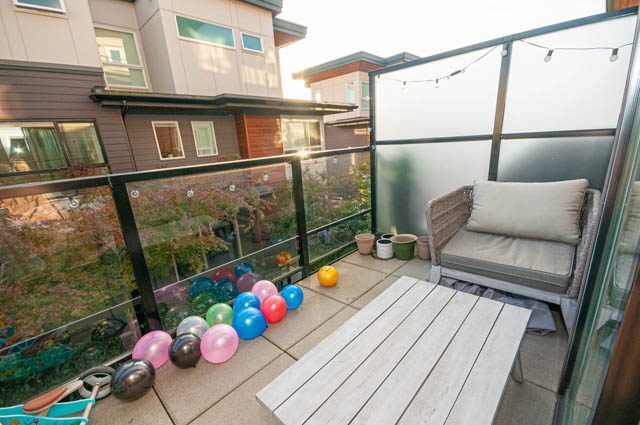 Furnished balcony with colorful balloons, patio furniture, and glass railings. - 30 - 533 East 3rd st., North Vancouver