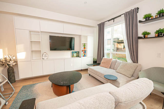 Spacious living room with modern furniture, large windows, and built-in entertainment center. - 30 - 533 East 3rd st., North Vancouver