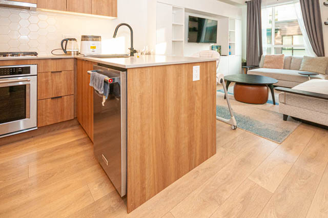 Bright kitchen with wooden countertops and hardwood floors, leading to a cozy living area with a sofa and coffee table.