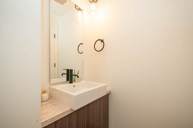 Bright bathroom with white sink, mirror, and wall-mounted towel rings. - 30 - 533 East 3rd st., North Vancouver