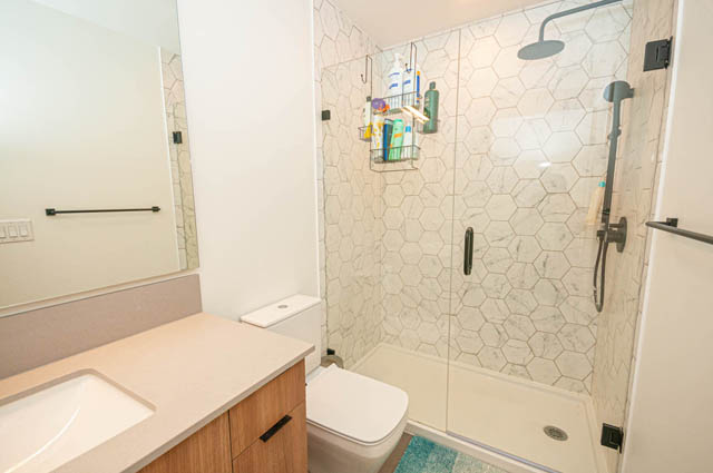 Modern bathroom with hexagonal tile shower and white countertops. - 30 - 533 East 3rd st., North Vancouver