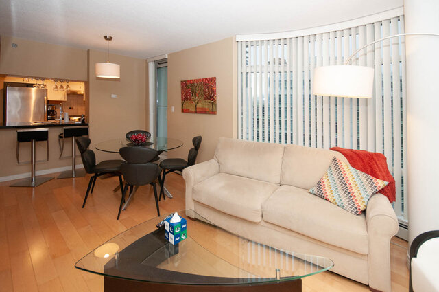 Open-concept living room with hardwood floors, modern furnishings, and a city view. - 1605 - 1199 Marinaside Crescent, Vancouver Downtown