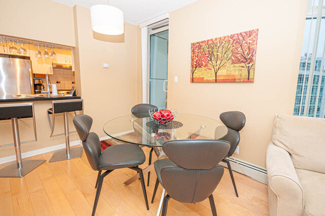 Modern dining area with glass table, contemporary chairs, and city view. - 1605 - 1199 Marinaside Crescent, Vancouver Downtown
