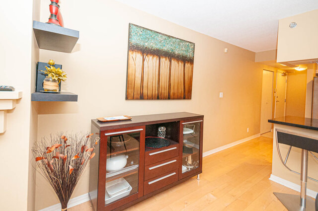 Spacious living room with modern decor, featuring hardwood floors, a sleek entertainment unit, and a vibrant abstract...