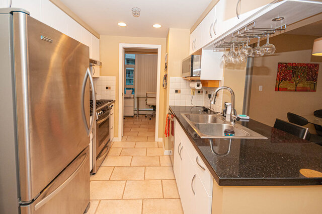 Bright kitchen with granite countertops, stainless steel appliances, and a view of the city. - 1605 - 1199 Marinaside Crescent, Vancouver Downtown