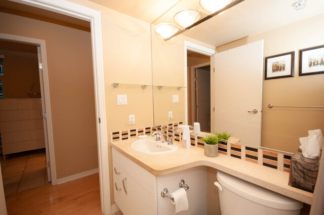 Spacious bathroom with light wood countertops, modern mirror, and a hint of city view. - 1605 - 1199 Marinaside Crescent, Vancouver Downtown