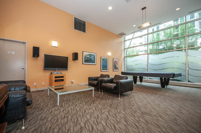 Spacious living room with a large TV, modern furniture, and frosted glass windows. - 1605 - 1199 Marinaside Crescent, Vancouver Downtown