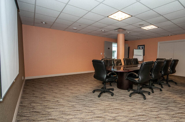 Spacious conference room with a long table, leather chairs, and a whiteboard, perfect for meetings.