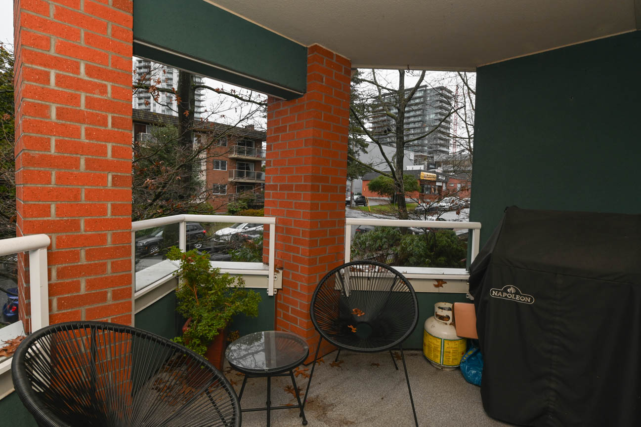 Furnished balcony with brick pillars, outdoor seating, and city view. - 208-128 8th Street West, North Vancouver