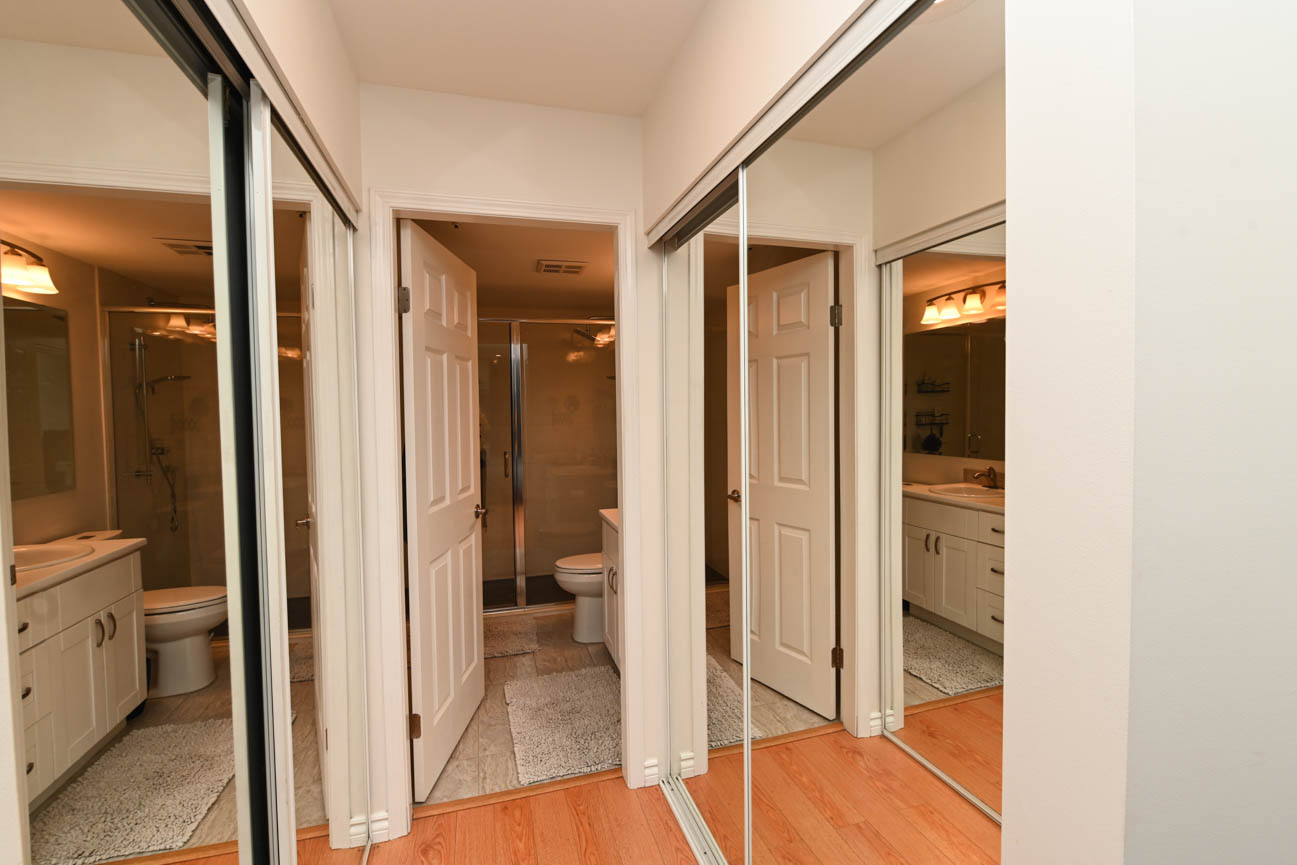 Furnished 2-bedroom condo with hardwood floors and a spacious bathroom featuring a walk-in shower and vanity.