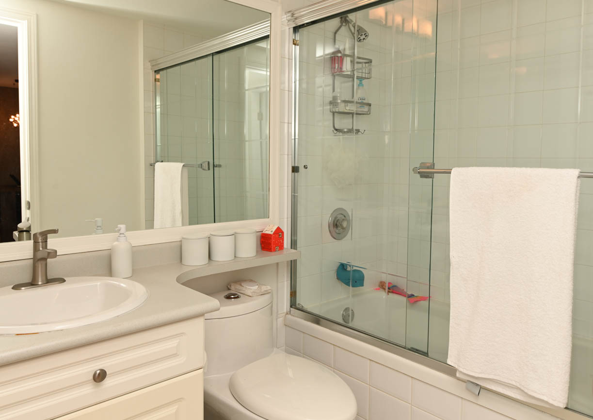 Furnished bathroom with white countertop and glass shower door. - 208-128 8th Street West, North Vancouver