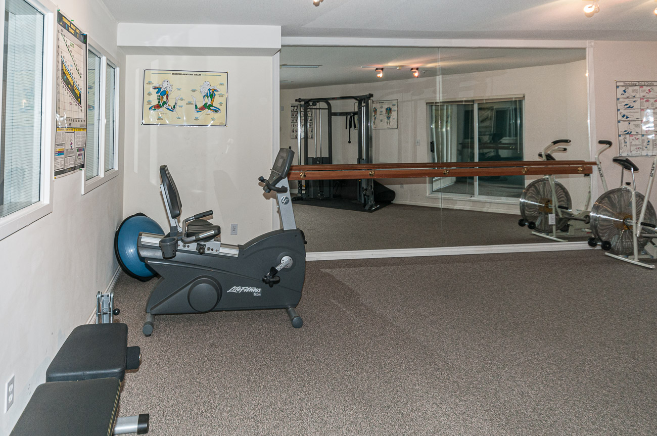 Bright exercise room with cardio equipment and mirrored wall, perfect for fitness enthusiasts. - 208-128 8th Street West, North Vancouver